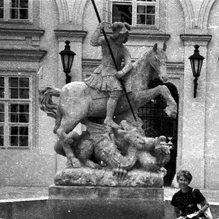 A person sitting on a historic fountain featuring a knight statue.