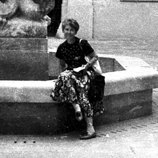 A person sitting on a historic fountain featuring a knight statue.