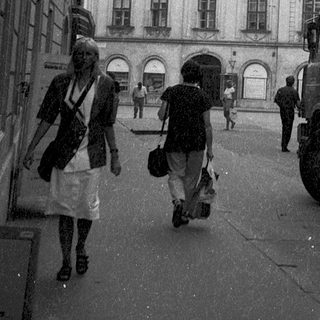 Historic European street scene with pedestrians, old architecture, and vintage truck.