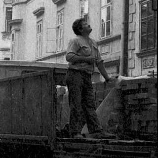 Historic European street scene with pedestrians, old architecture, and vintage truck.