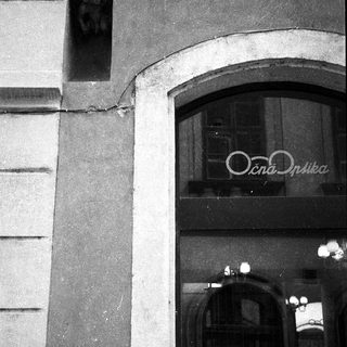 Statue above storefront entrance with sign "Очна Оптика".