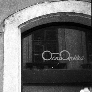 Statue above storefront entrance with sign "Очна Оптика".