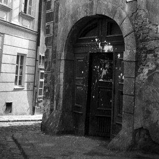Historic European street with arched entrance and old buildings.