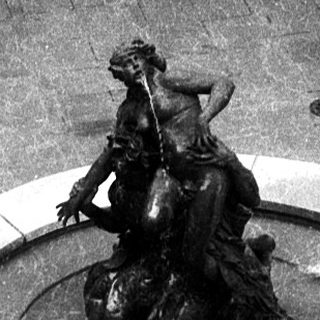 "Courtyard fountain with classical statue and modern sculpture."