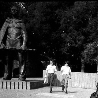 People walking near historical statues in park.