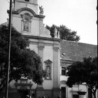 Historic building facade with classical architecture, people walking outside.