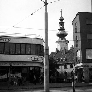 Urban street scene with historic church tower and modern buildings.