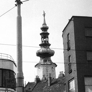 Urban street scene with historic church tower and modern buildings.