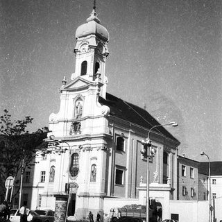 Neoclassical church with bell tower, urban setting.