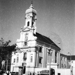 Neoclassical church with bell tower, urban setting.