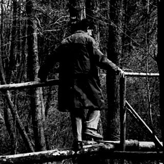 People crossing a rope bridge over a flowing stream.