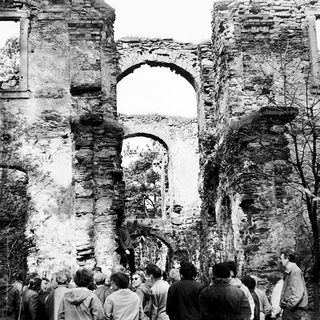 Ruins of an old stone building with gathered people.