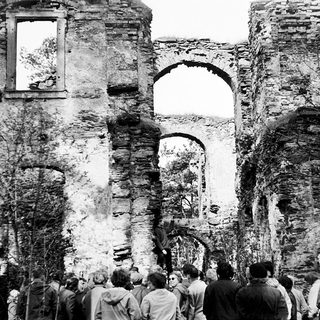 Ruins of an old stone building with gathered people.