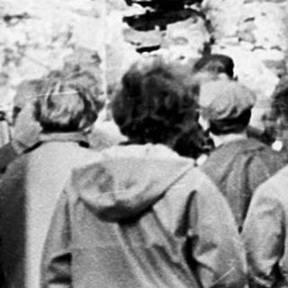 Ruins of an old stone building with gathered people.