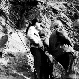 Two men examining exposed rock layers outdoors.