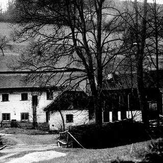 Rural farmhouse in hilly countryside setting.