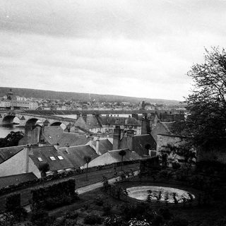 Historic town view with rooftops, bridge, and river.
