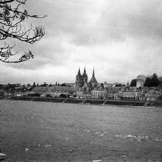 Historic town by river with cathedral spires.