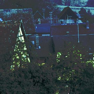 Rural village with church steeple and thatched roofs.