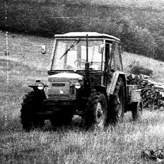 Vintage tractor transporting hay in rural field.
