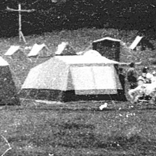 People camping outdoors in a field with tents.