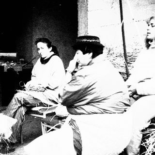 Group of people engaged in traditional textile work indoors.