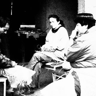 Group of people engaged in traditional textile work indoors.