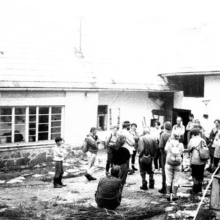 People gathering outside damaged building during cleanup.