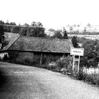 Rural village scene with road, houses, and open fields.