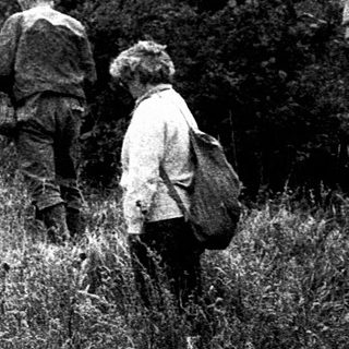 People hiking near a rocky cliff.