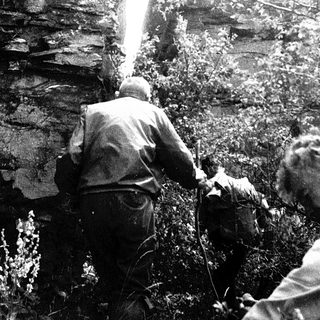 Two men rappelling down a rocky cliff.
