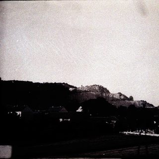 Rural landscape with hill, houses, and open fields.
