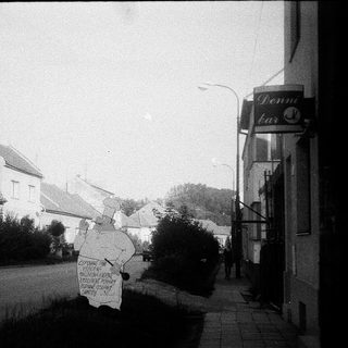 Vintage street scene with protest sign near bar.