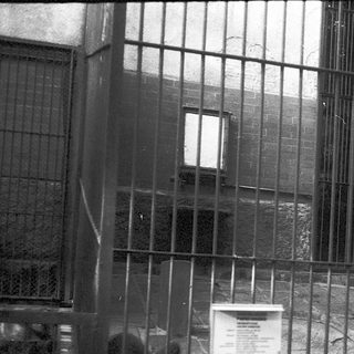 Prisoner exercise area behind barred fence.