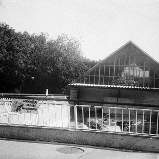 Greenhouse structure with signage near roadside fence.