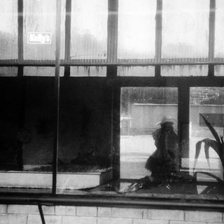 Person sitting alone outside on rainy day.