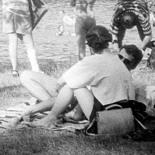 People enjoying lakeside swimming and sunbathing.