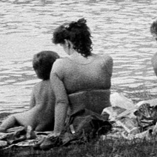 People enjoying lakeside swimming and sunbathing.