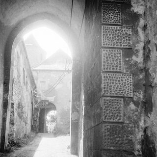 Narrow stone alleyway with arched entrance.