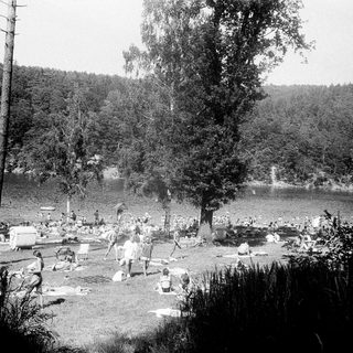 Lakeside gathering with people relaxing by water.