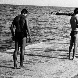 People swimming and relaxing by the seaside.