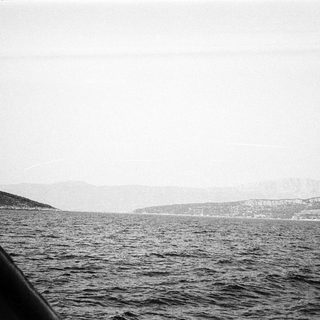 Coastline viewed from water, misty horizon.