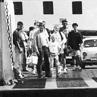 Person standing by ferry dock with luggage.