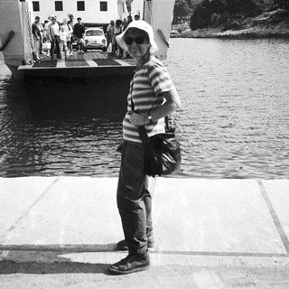 Person standing by ferry dock with luggage.