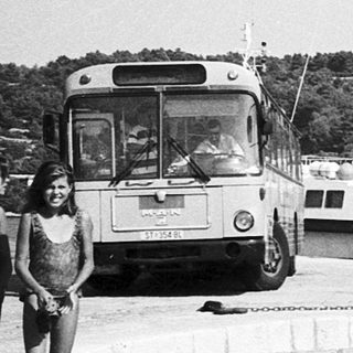 Two women by waterfront with boats and ferry.