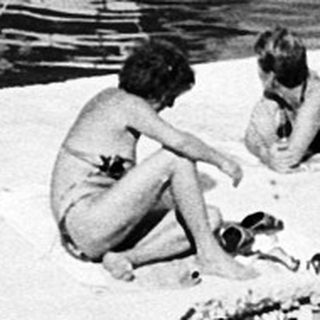 Boats docked near shoreline with people relaxing.