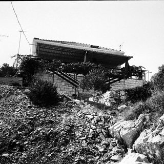 Damaged house on unstable, landslide-affected terrain.