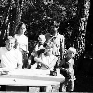 Family gathering outdoors in a wooded area.