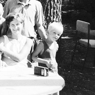 Family gathering outdoors at picnic table.