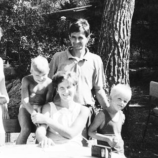 Family gathering outdoors at picnic table.